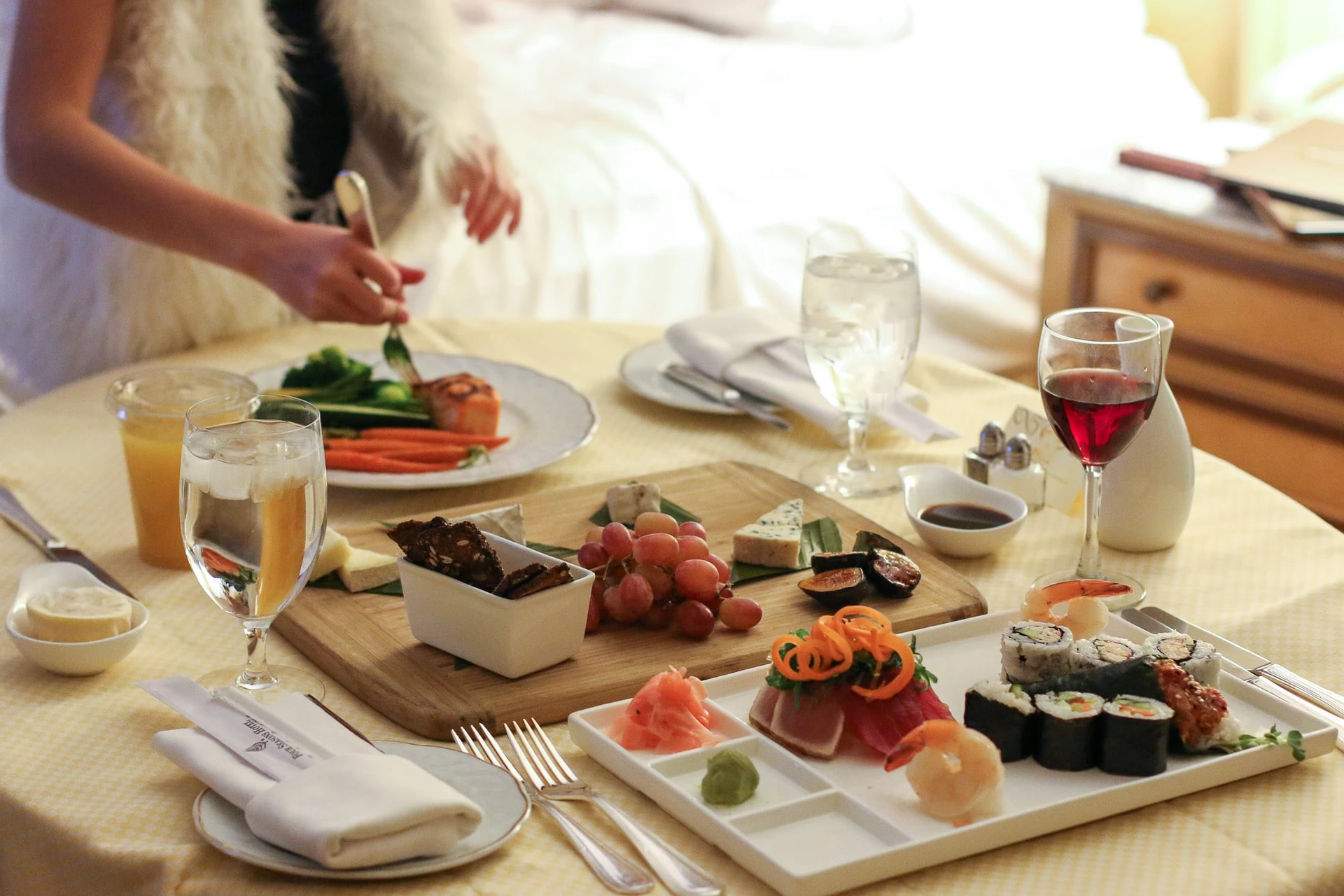 In-room dining tray with a cheese plate, sushi, seared ahi and more on top.