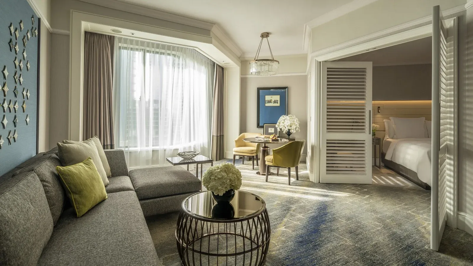 Executive Suite living room view into the bedroom with soft blues and neutral decor.