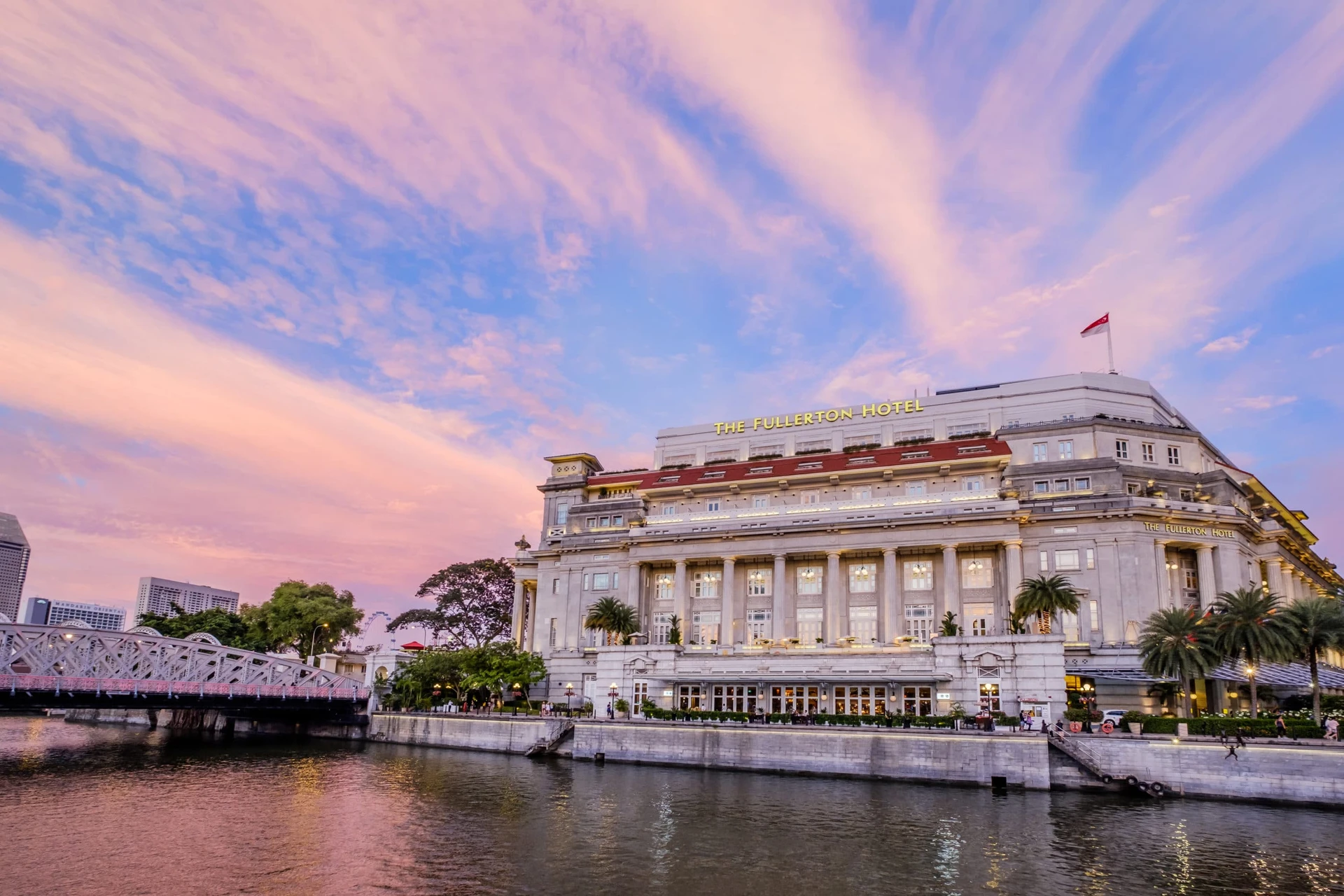 A view of The Fullerton Hotel's colonial exterior from across Marina Bay at sunset.