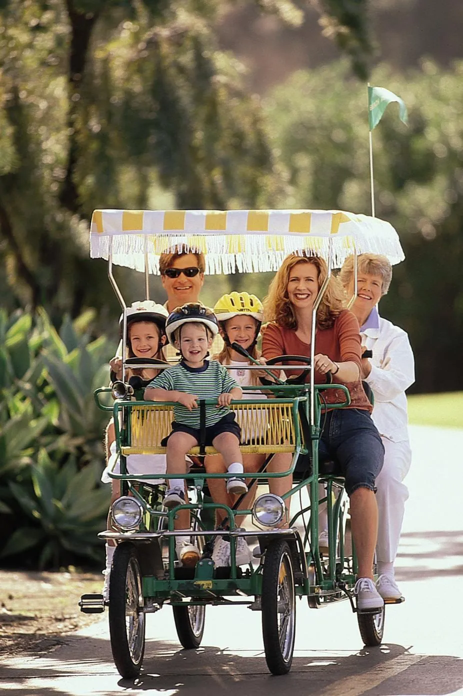 A multigenerational family riding a surrey bike down a sidewalk in Santa Barbara.