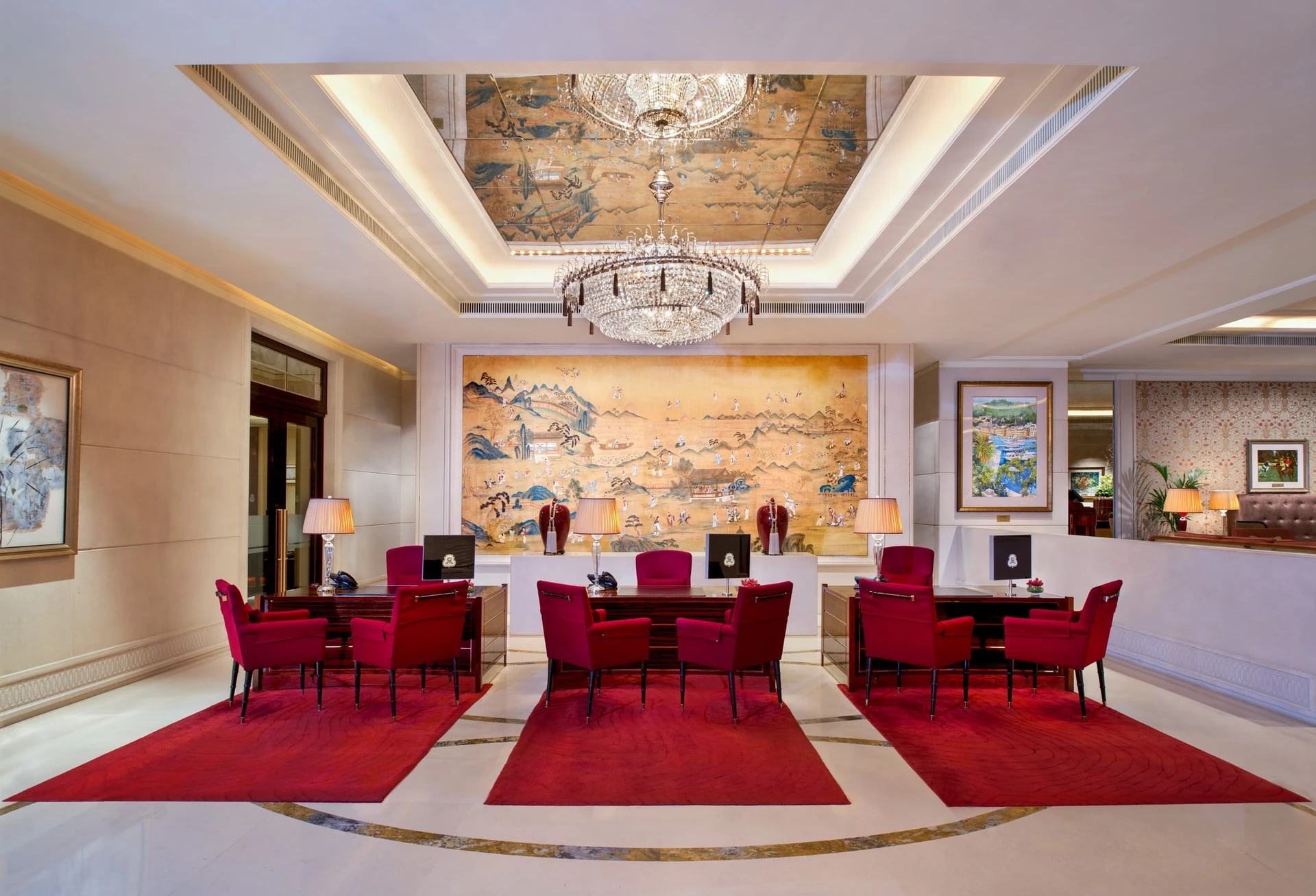 The lobby at St. Regis has deep red velvet chairs and rugs in addition to a gold Asian painting and crystal chandelier.