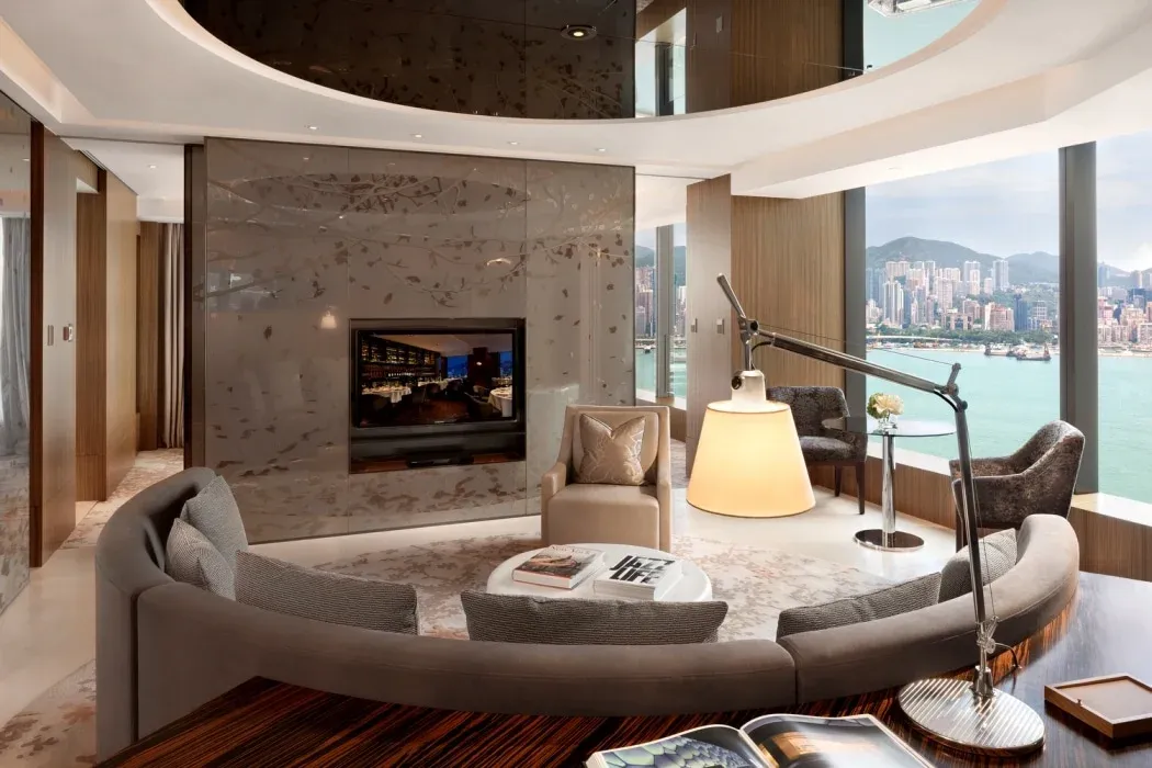 The living room with rounded sofa and Victoria Harbour views of a Club 80 Harbour Suite.