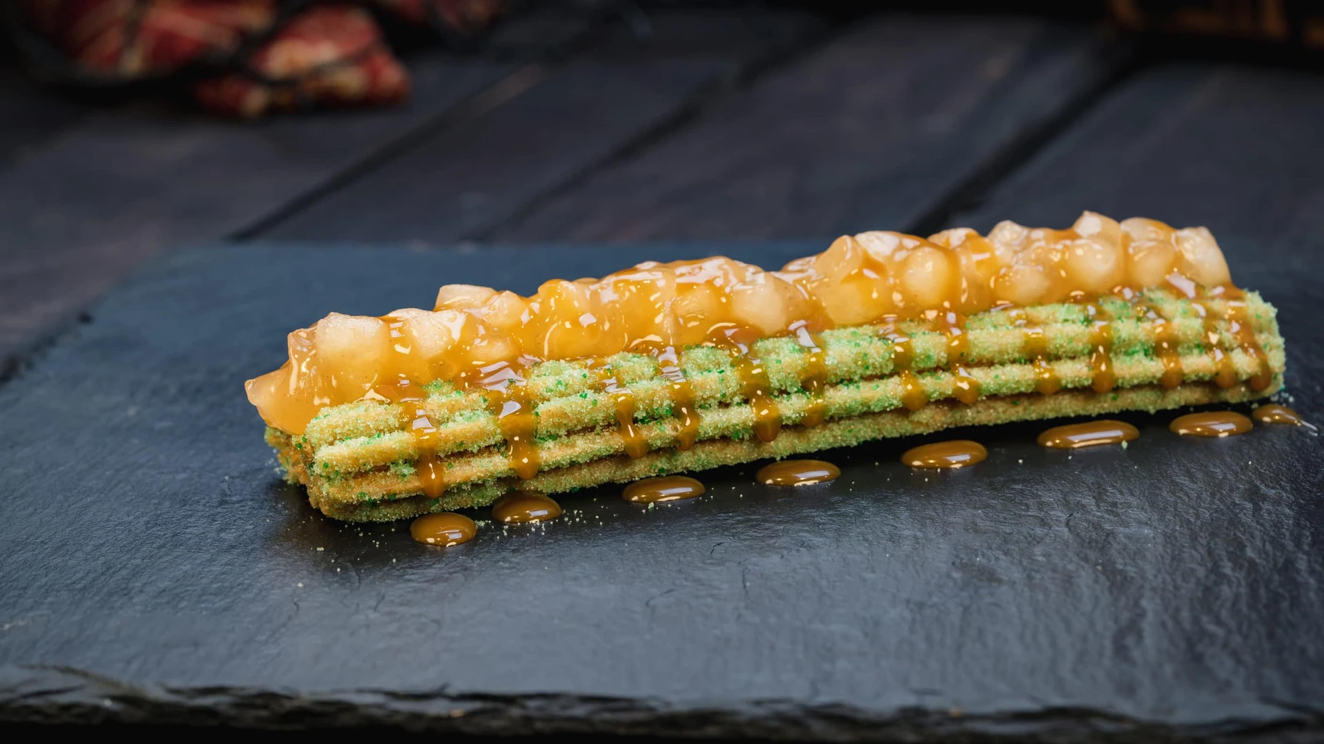 Churro with green sprinkles topped with apples and caramel sauce.