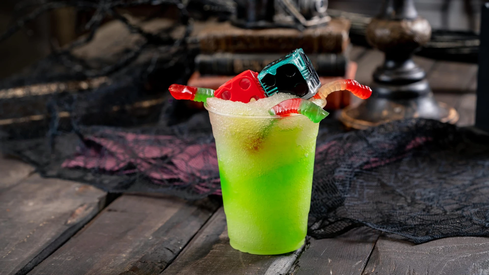 The green Oogie Bookie-inspired drink with dice and gummy worms on top.