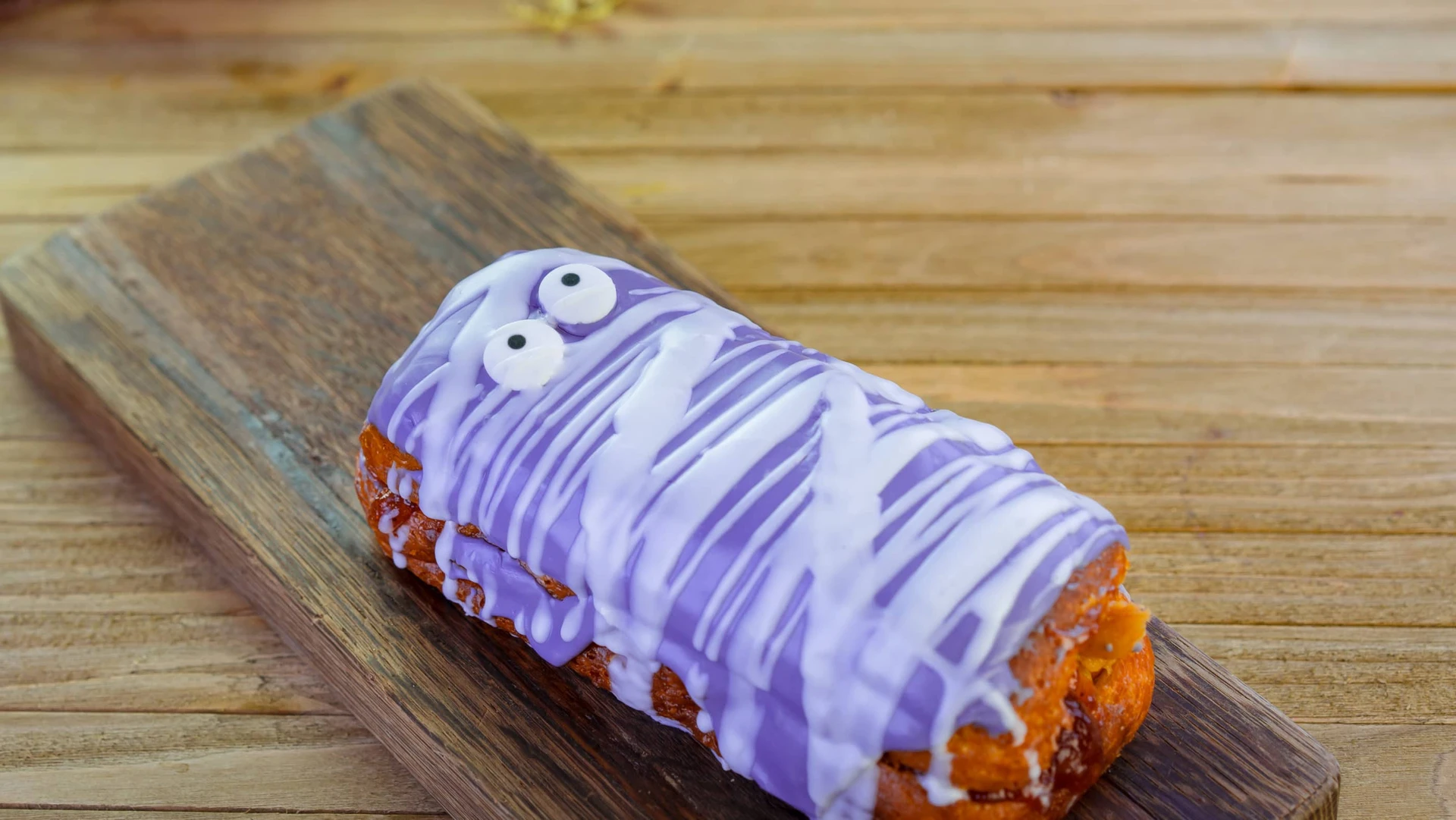 Donut with purple icing, white mummy wrap and white eyeballs.