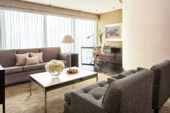 The seating and desk area of the One-Bedroom Suite at Four Seasons Hotel Tokyo at Marunouchi features neutral tones.