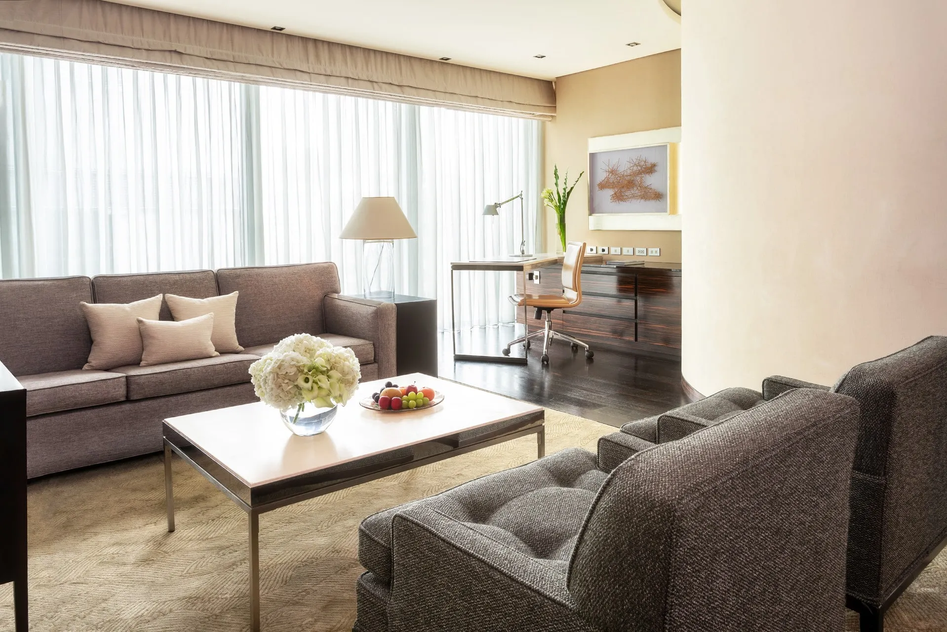 The seating and desk area of the One-Bedroom Suite at Four Seasons Hotel Tokyo at Marunouchi features neutral tones.