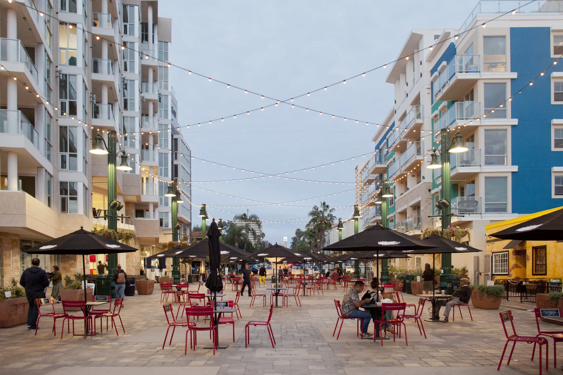 A piazza with red tables and chairs in Little Italy San Diego.
