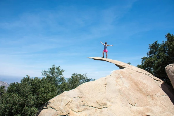 A hiker stands on potato chip rock in San Diego.