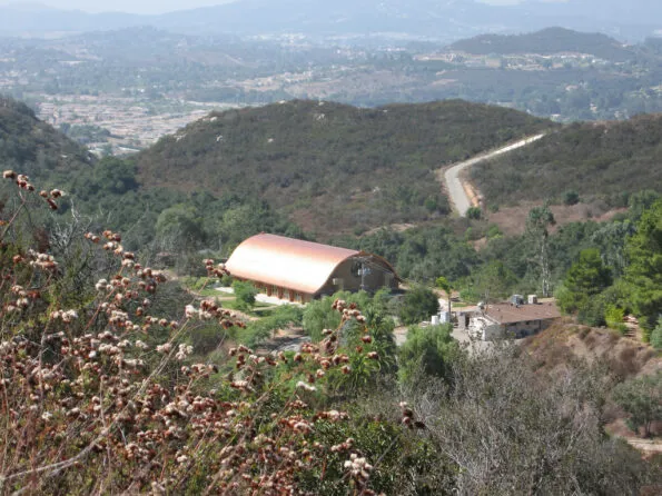 The main building with its copper-colored roof set in the middle of of a rural landscape.
