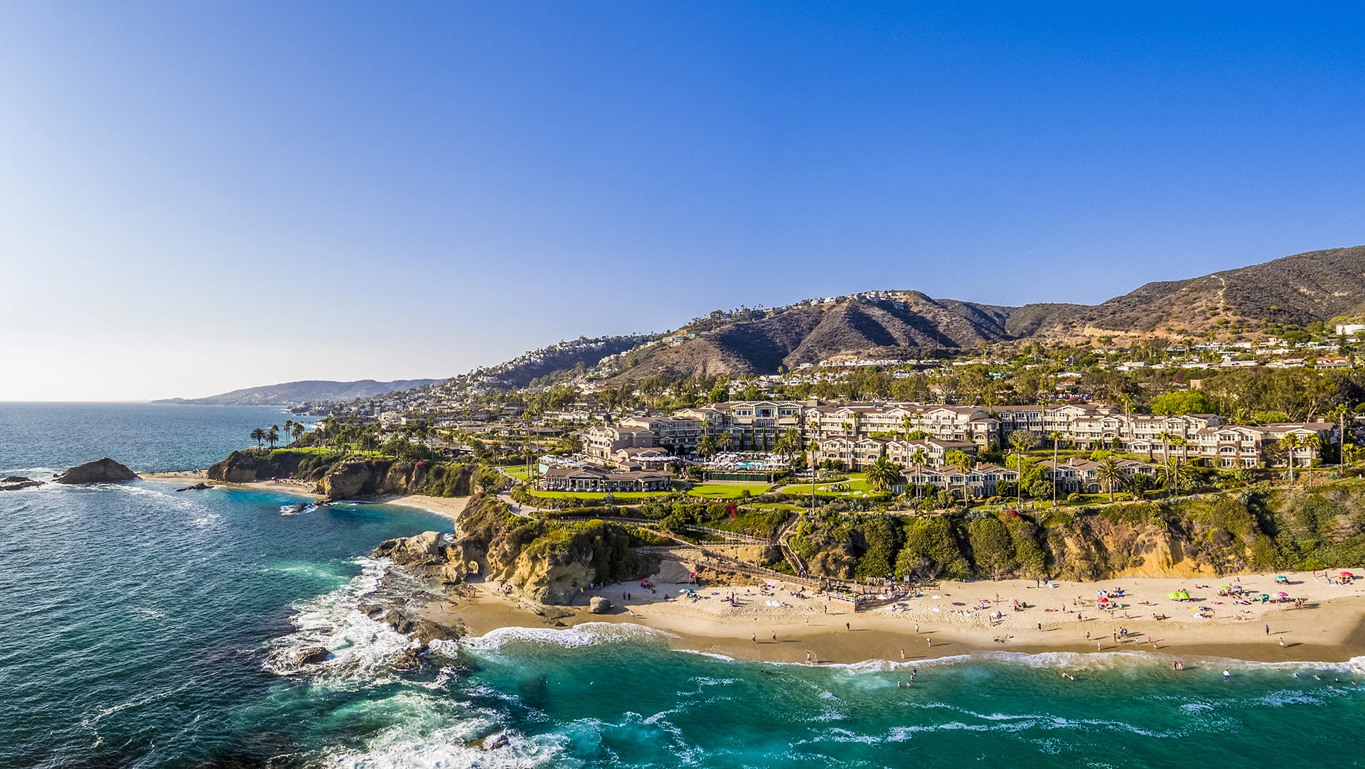 View from the water to the beachfront resort set on top of small bluffs above the sand.