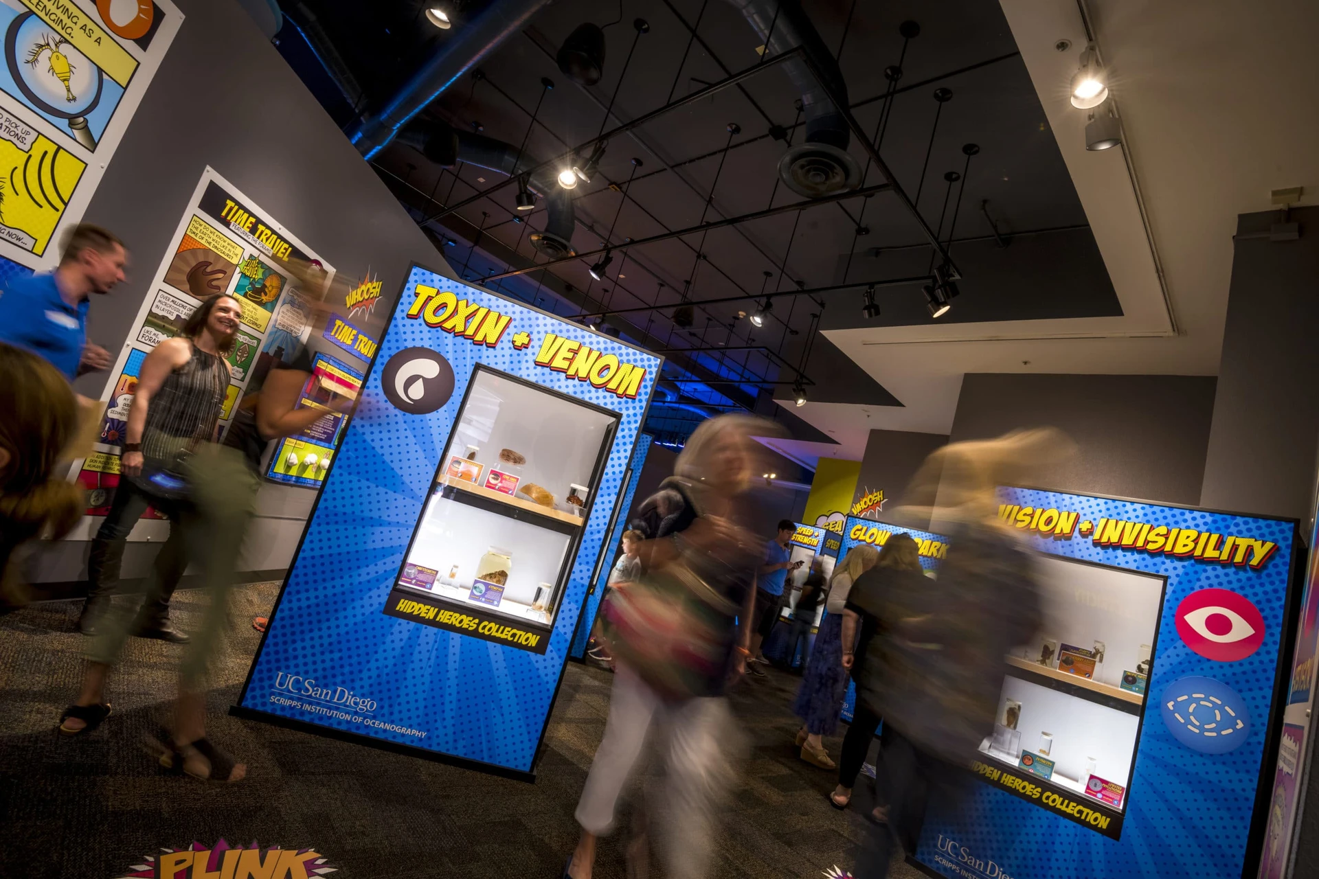 Guests walk through purple displays filled with sea creatures and comic book art explanations in Oddities.