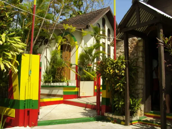 The exterior, with red, yellow and green stripe accents on poles, stairs and gates, to the Bob Marley Mausoleum.