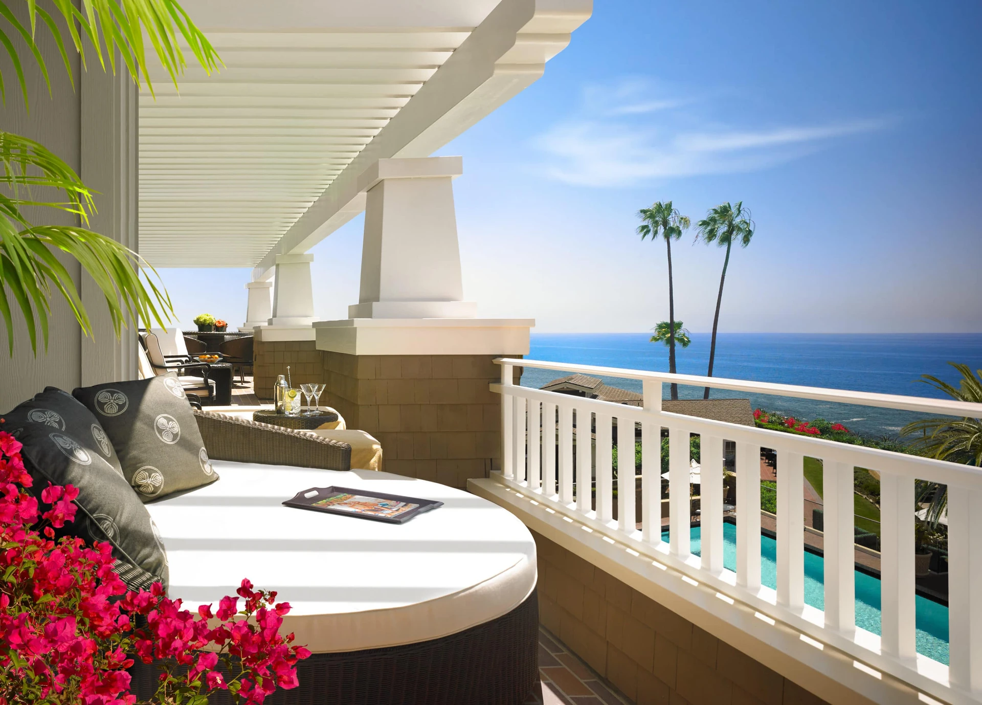 A day bed with pillows on the balcony of the Catalina Suite overlooks the spa pool and ocean.