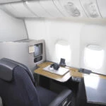 A first class chair on a Boeing 777 turned to face the window and desk in office mode.