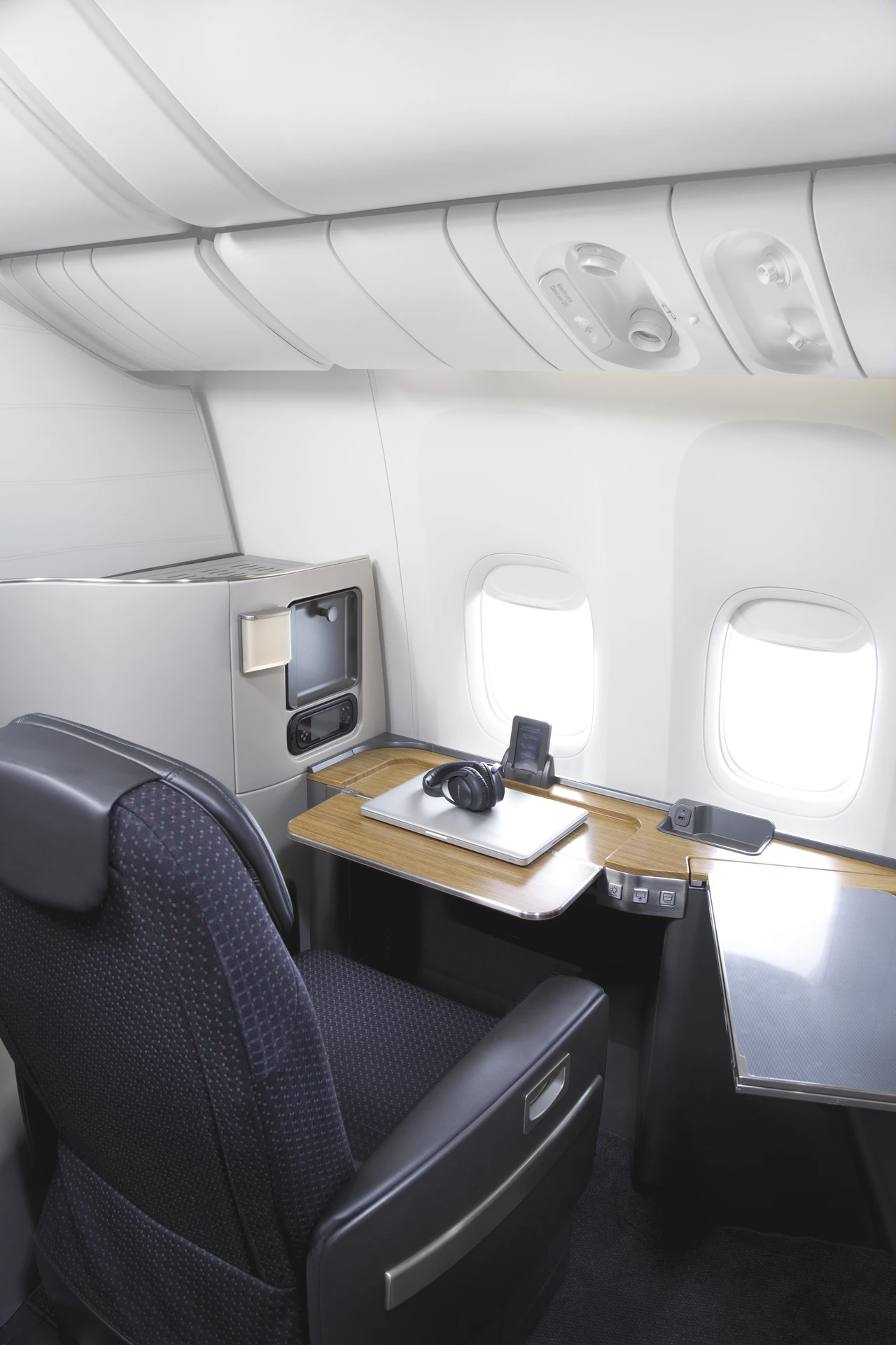 A first class chair on a Boeing 777 turned to face the window and desk in office mode.