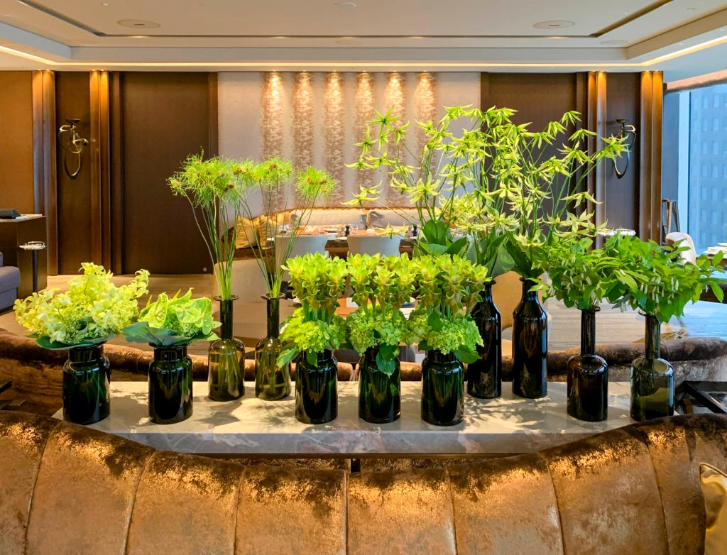 Multiple black vases full of various green flowers serve as the focal point of Motif restaurant.