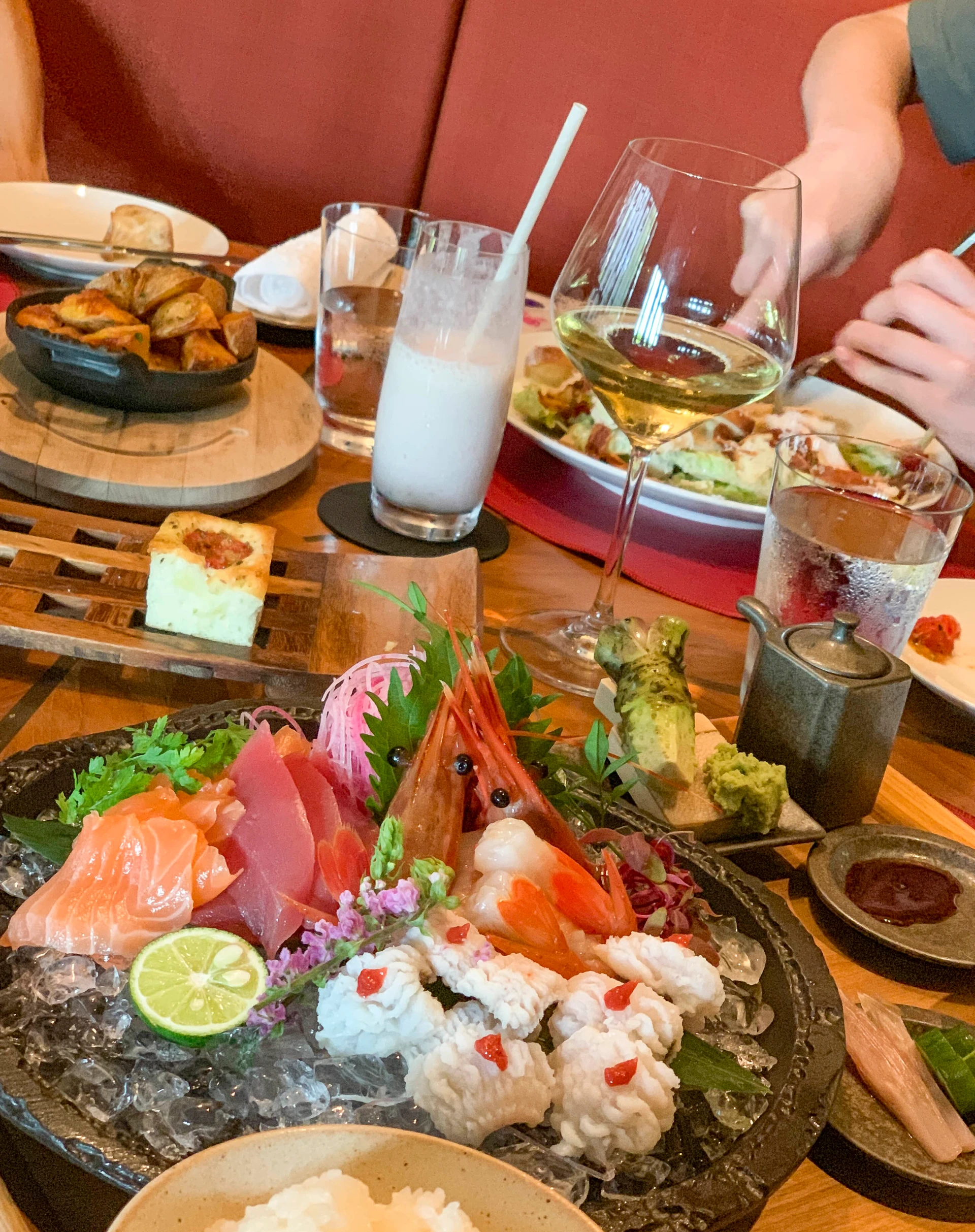 A platter of five types of fish on ice on the table with grate-your-own wasabi and fresh ginger.