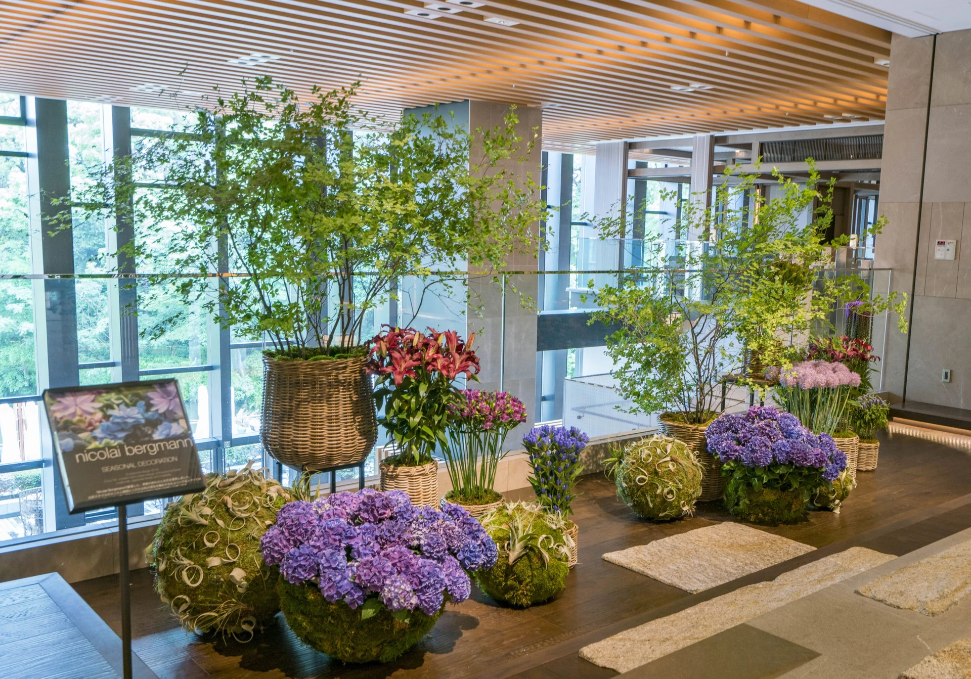Moss orbs and spheres with flowers sit in front of baskets full of live arrangements in the lobby at Four Seasons Kyoto