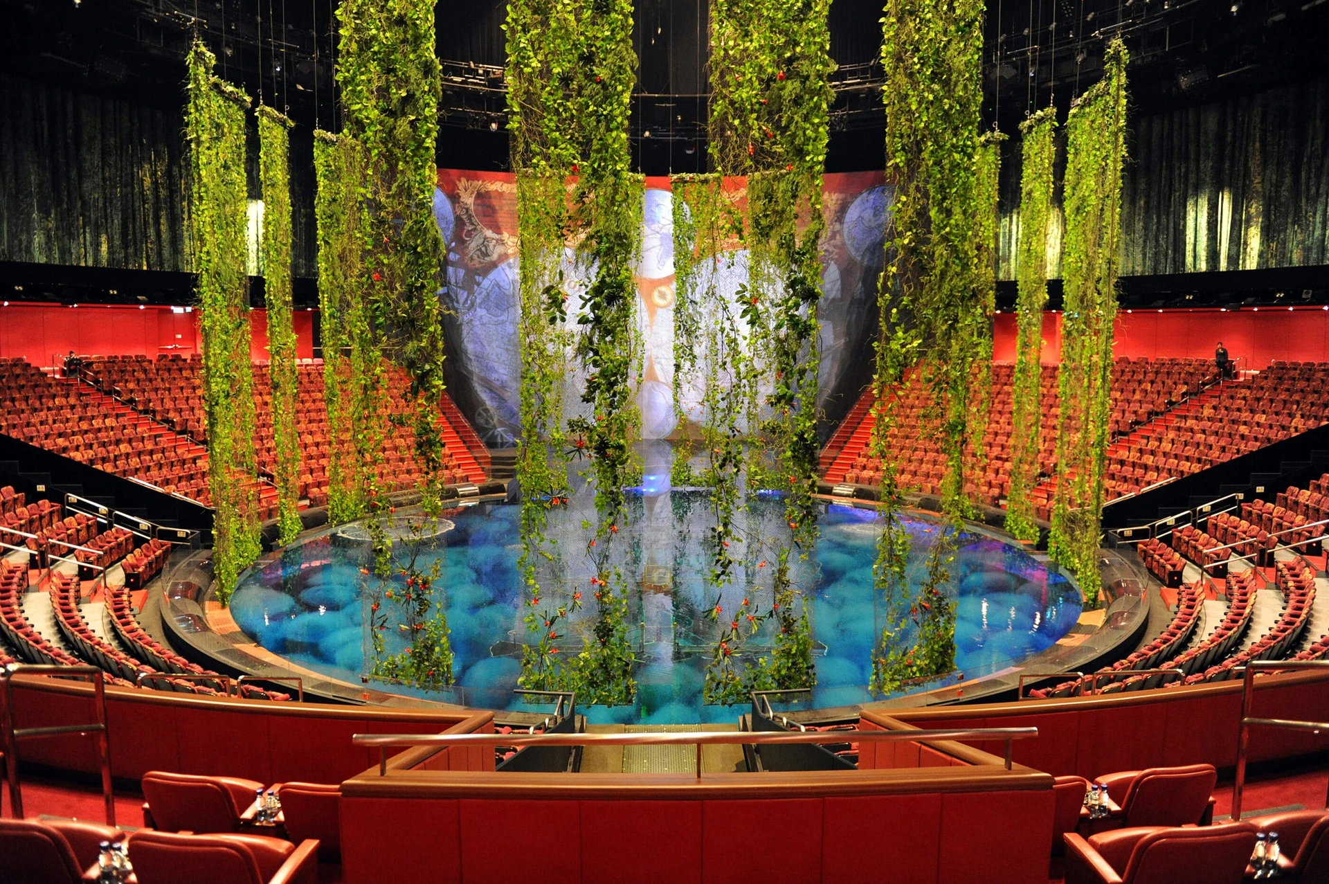 The theater pool filled with water surrounded by empty seating as they prepare for a show.