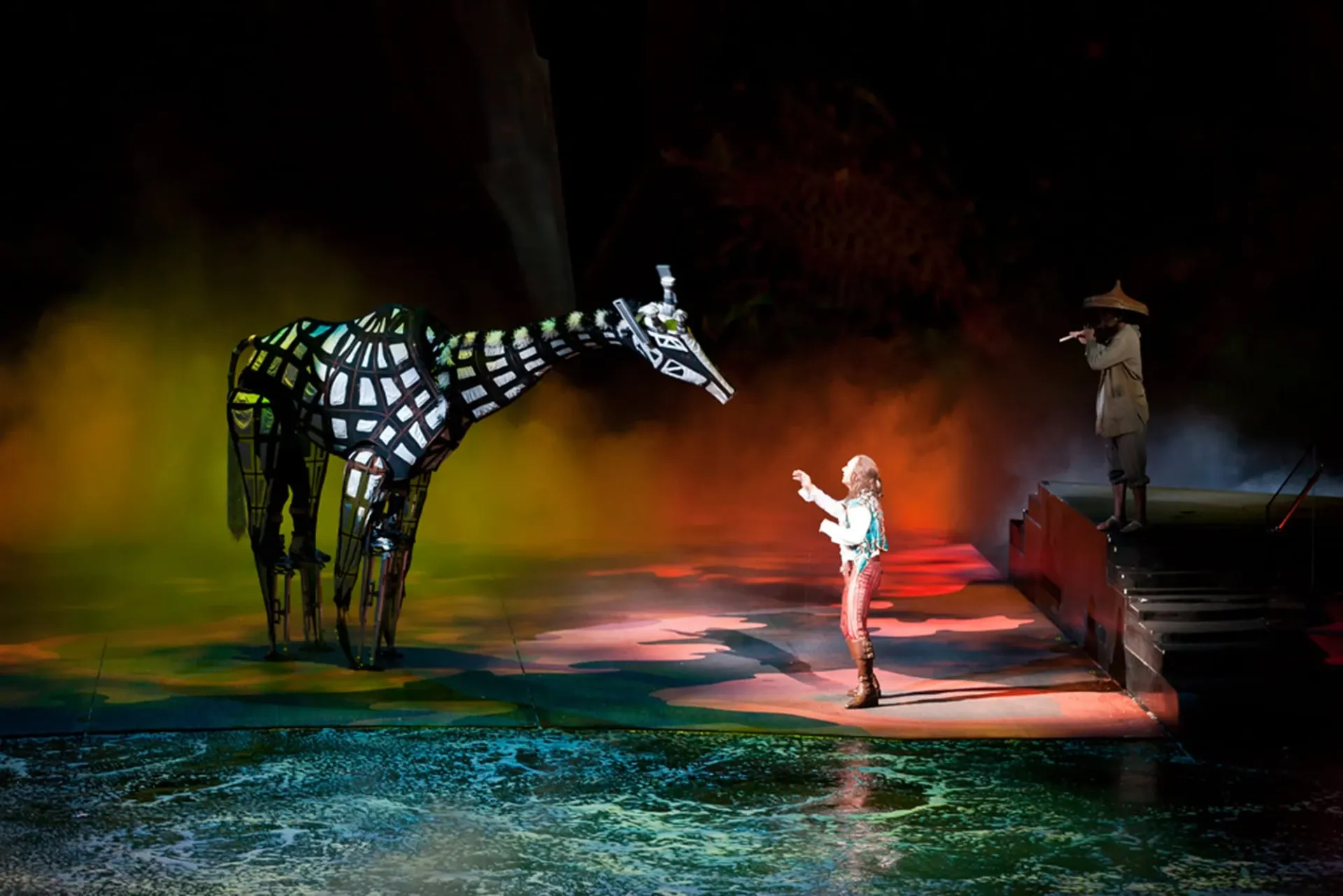 A mystic giraffe character and stranger on stage.