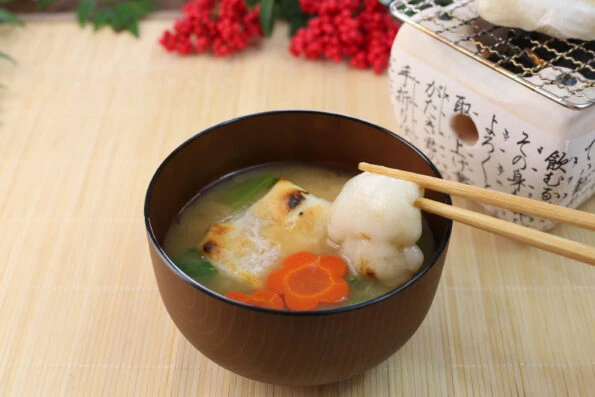 Chopsticks lifting gooey mochi out of a bowl of ozone soup.