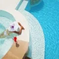 A woman relaxing in a jaccuzzi next to a swimming pool.