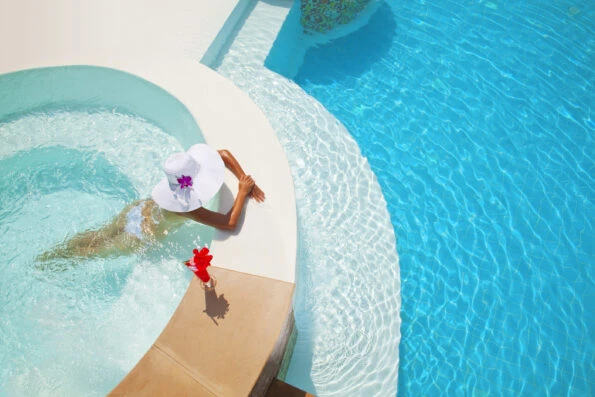 A woman relaxing in a jaccuzzi next to a swimming pool.