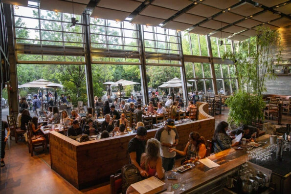 People gathered at the bar and seated at indoor and outdoor tables on a busy day at Stone Brewing.