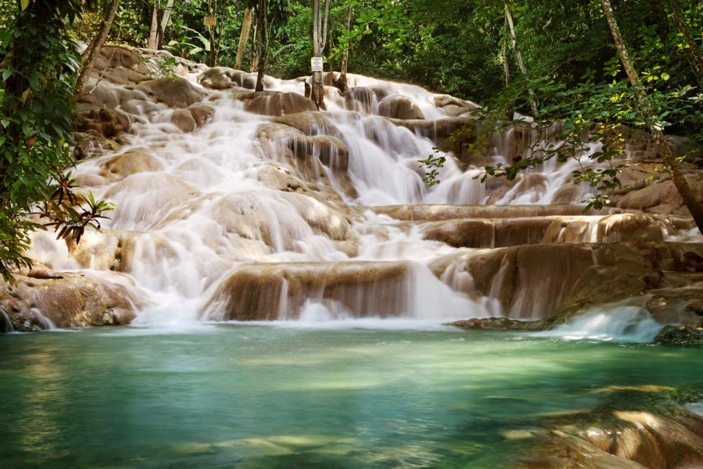 Dunn's River Falls flowing over rocks into a turquoise pool of water.