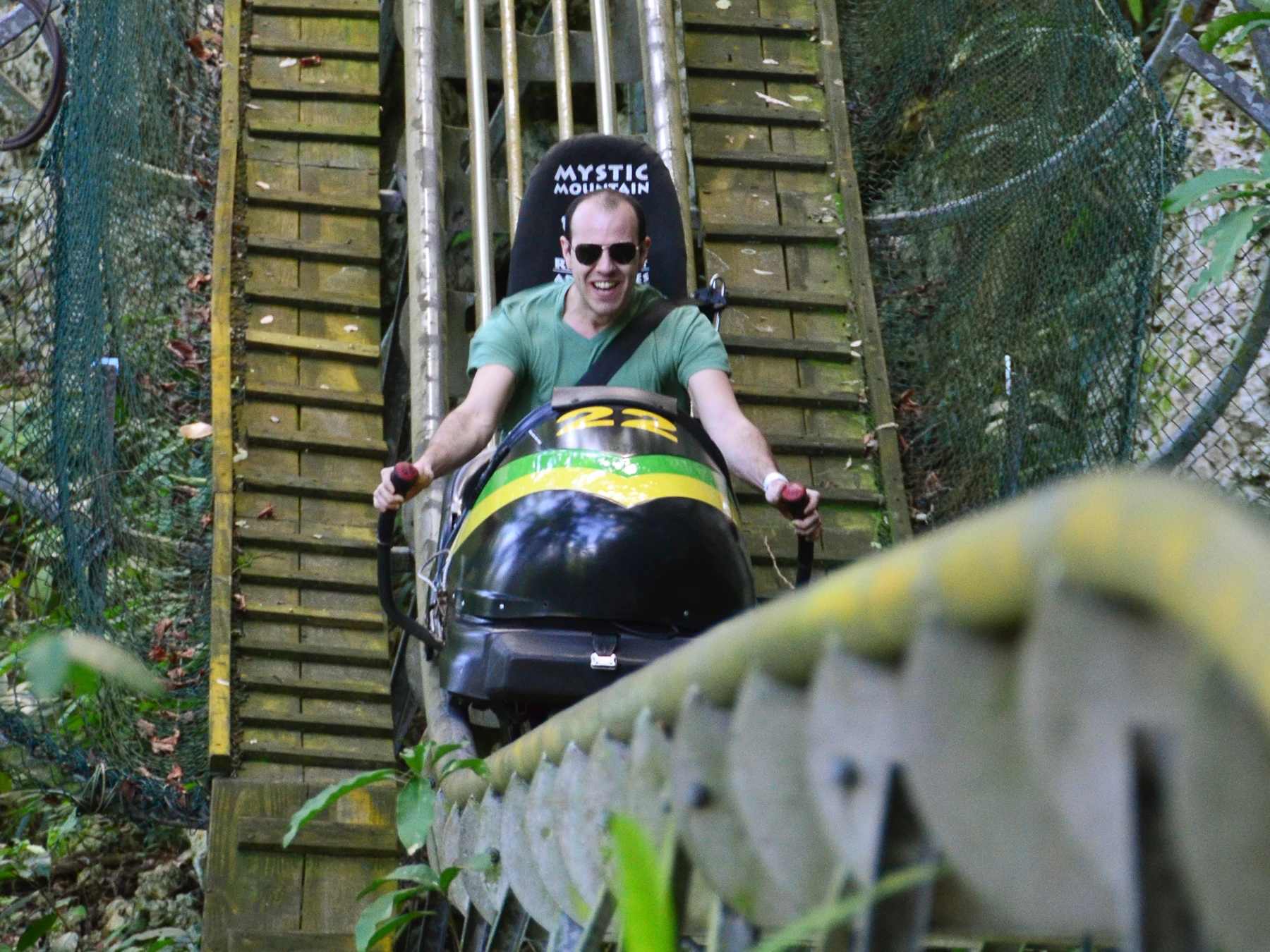 A man rides in a bobsled down a track.