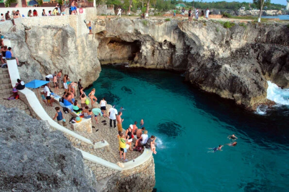 Aerial view of people watching others dive off of the famous cliff into the blue water at Rick's Cafe.