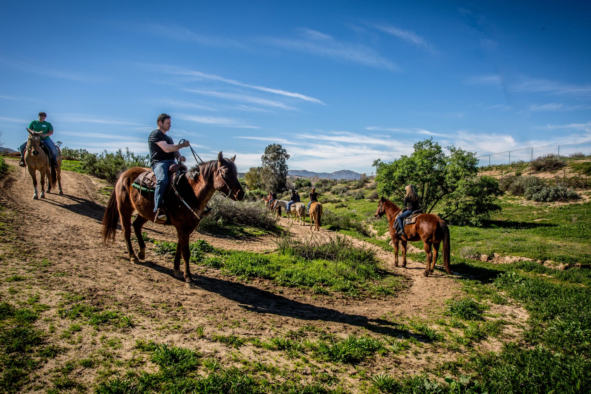 A group horseback riding on a trail in Temecula Valley.
