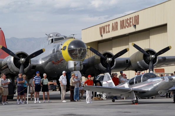 Guests stand outside under a large vintage aircraft.