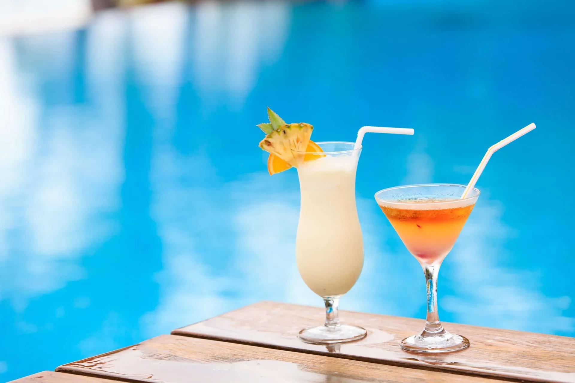 Two tropical drinks at the edge of the pool