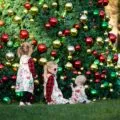 Three little girls sit in front of the big Christmas tree at Fairmont Grand Del Mar