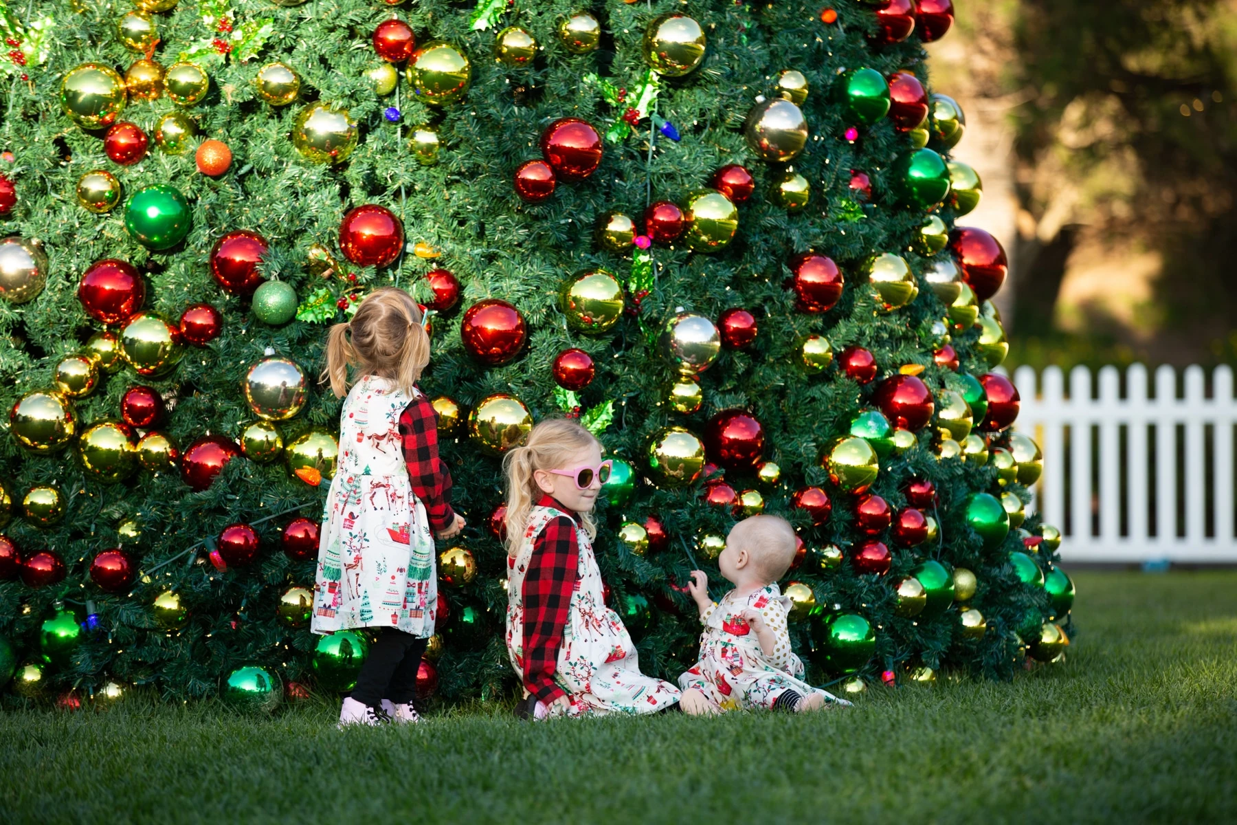 Three little girls sit in front of the big Christmas tree at Fairmont Grand Del Mar