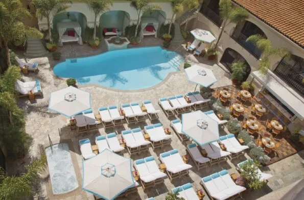 Overhead shot of the Mediterranean-style pool surrounded by white lounge chairs with blue accents at Beverly Wilshire.
