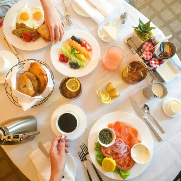 Downward shot of a Beverly Wilshire room service table with plates or fruit, eggs, lox and bagels.