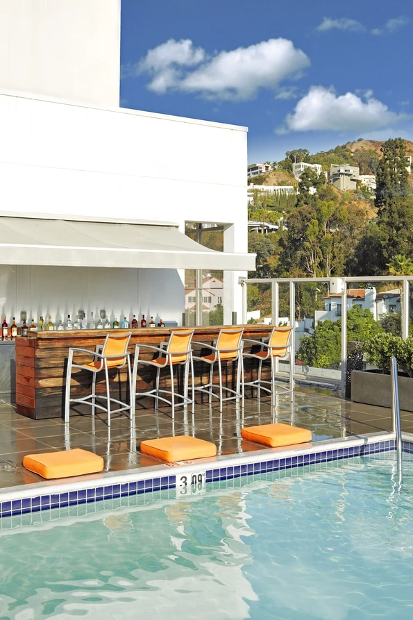 The chic pool bar with orange barstool chairs near the water's edge.