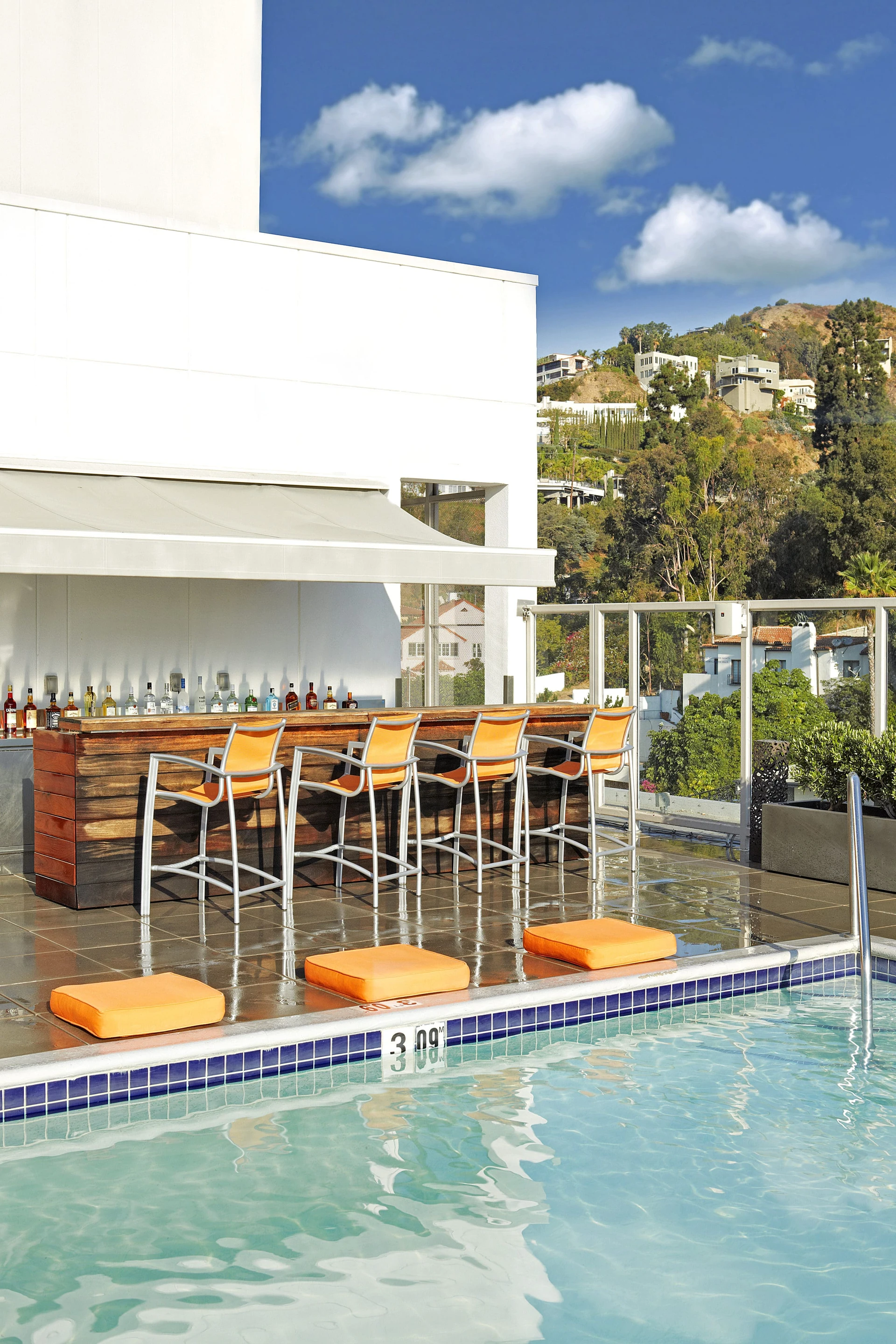 The chic pool bar with orange barstool chairs near the water's edge.