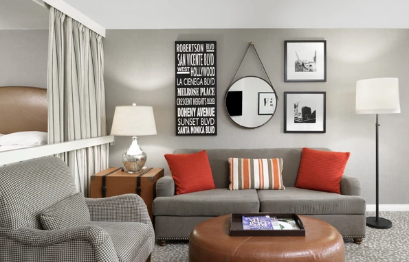 A suite living room with grey seating, orange throw pillows.