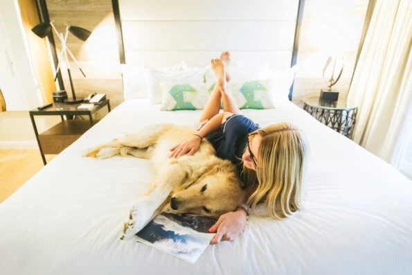A woman relaxes with her dog on a bed at San Diego Mission Bay Resort.
