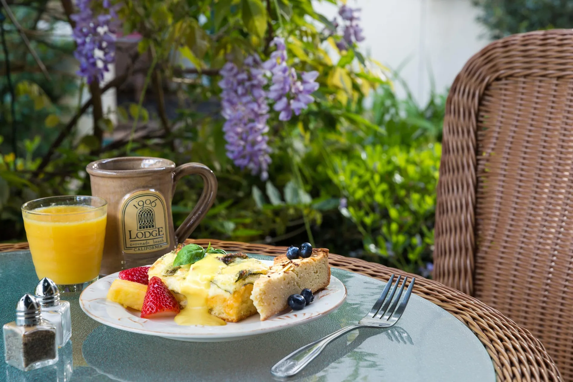 Plated breakfast next to orange juice and coffee on a table in the courtyard at 1906 Lodge Coronado