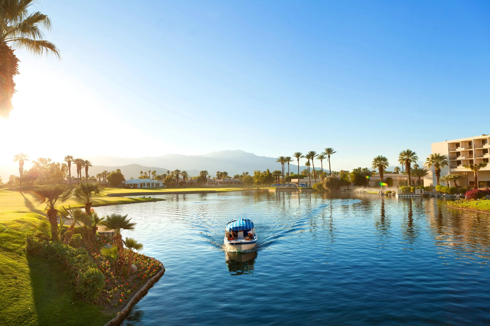 A small boat sails through a large lake on the property of JW Marriott Desert Springs.