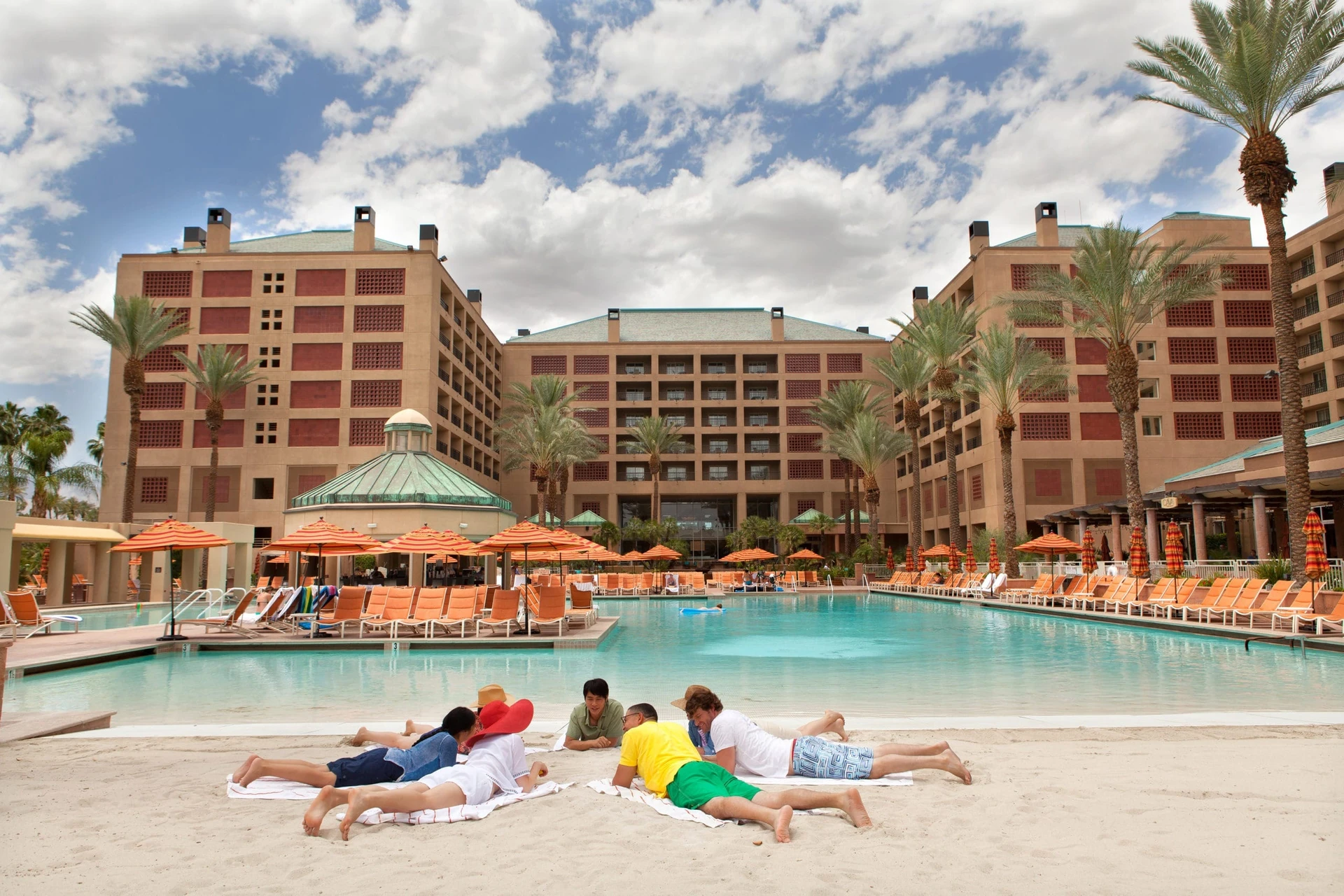 Adults lay in the sand like they're having a meeting near the pool at Renaissance Esmeralda Indian Wells.
