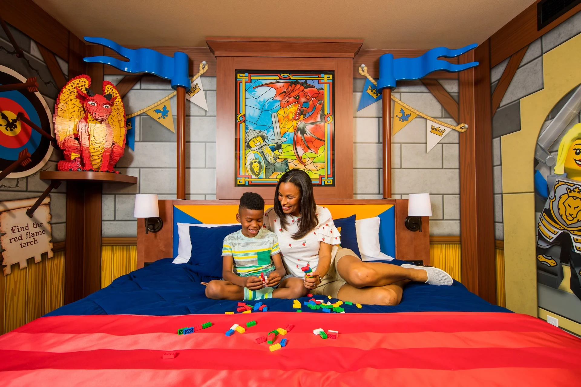 A mom and son play LEGOs on the bed in a Knight Room at LEGOLAND Castle Hotel, a popular kid-friendly San Diego hotel.
