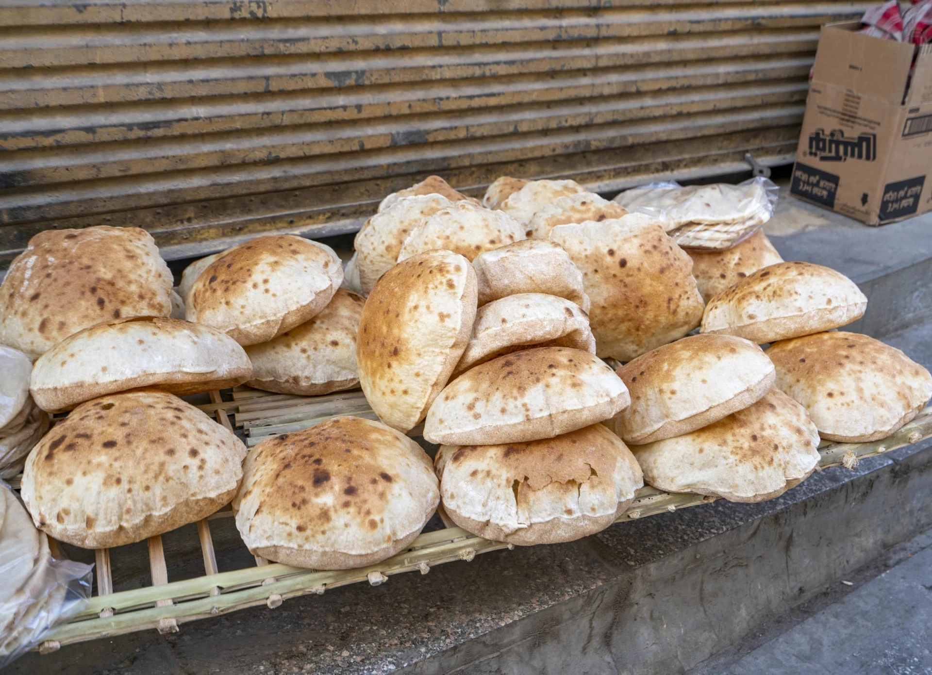 Aish (Egyptian bread) piled on a street side rack with no cover.