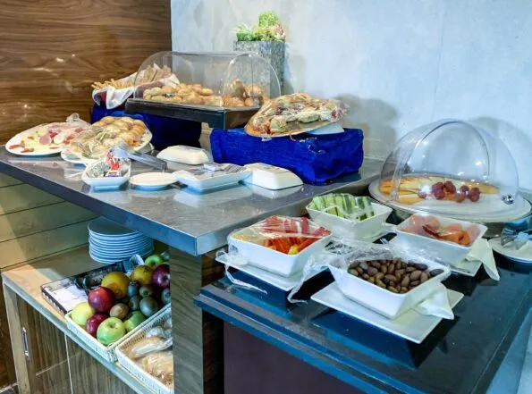 Small buffet of finger sandwiches, pastry, vegetables, fruit and cheese inside the EgyptAir Gienah lounge at Cairo Airport.