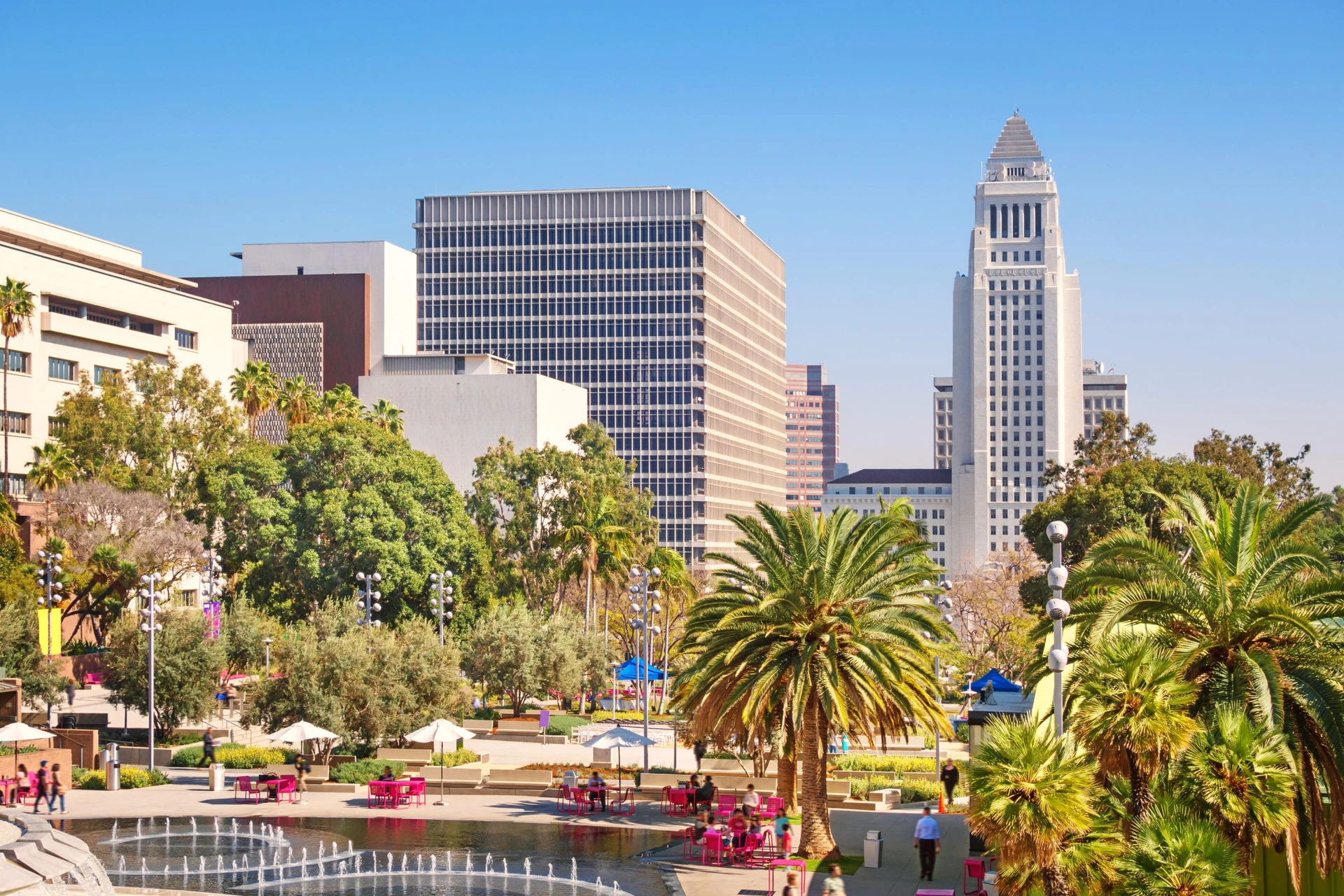 People out enjoying the sunshine at tables near a lake in Grand Park Los Angeles.